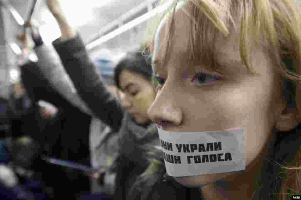 A woman takes part in a flash mob in the Moscow subway, with a sticker on her mouth saying, &quot;They stole our voices.&quot; (ITAR-TASS/Aleksandr Sorin)