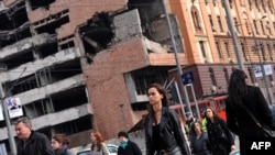 Serbia -- Pedestrians cross a street in Belgrade near the former federal military headquarters destroyed during the 1999 NATO air campaign against Yugoslavia, March 10, 2014. Photo by Andrej Isakovic (AFP).