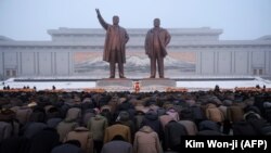 Locuitori din Phenian îngenunchiați în fața statuilor lui Kim Ir-Sen i Kim Jong Il de Ziua Națională pe dealul Mansu în Phenian, 17 decembrie 2018 (foto KIM Won Jin / AFP)