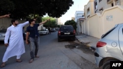 Abdullah al-Raghie (left) and Abdul Moheman al-Raghie, the sons of Al-Qaeda suspect Abu Anas al-Libi, point at the house next to the scene where their father was seized by U.S. forces in a commando raid in Nofliene.