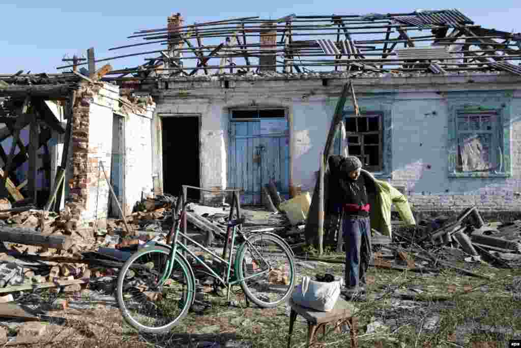 Донецк маңындағы Карловка селосында атыс салдарынан қираған&nbsp;тұрғын үйдің жанында тұрған әйел. 30 қазан 2014 жыл. 