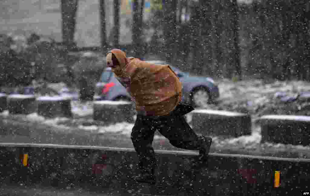 A Pakistani man crosses a street during snowfall in Murree, some 65 kilometers north of Islamabad. (AFP/Aamir Qureshi)