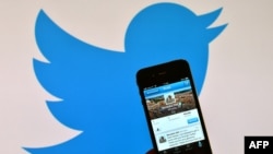 "Twitter" sosial ulgamynyň logotipiniň öňünde ýerleşdirilen smartfon