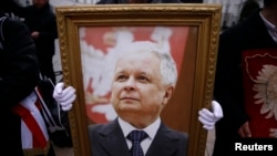  Мъж държи фотография на починалия полски президент Лех Качински по време на възпоменателна гала за самолетната злополука през 2010 година пред президентския замък във Варшава. 10 февруари 2016 година 