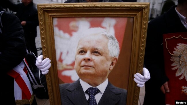 Мъж държи снимка на покойния полски президент Лех Качински по време на възпоменателна церемония за самолетната катастрофа през 2010 г. пред президентския дворец във Варшава. 10 февруари 2016 г.