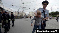 Un polițist escortează un adolescent care a participat la un protest în St. Petersburg, 9 septembrie 2018