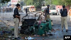Police officials stand beside a mangled auto-rickshaw at the site of a suicide bomb attack in Peshawar.
