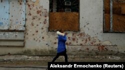 A woman walks past a store damaged by shelling in the separatist-held city of Donetsk in eastern Ukraine. (file photo)