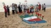کودکان جزیره ابوموسی در حال شادی در اطراف پرچم ایران بر روی شن‌های ساحل خلیج فارس
