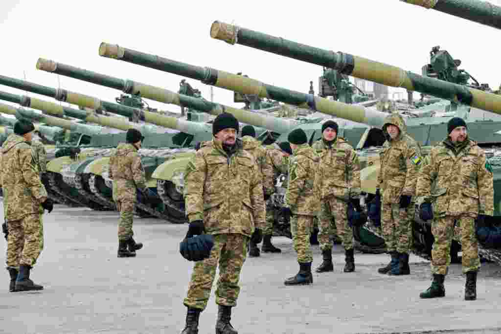 Ukrainian servicemen stand near tanks after a ceremony with Ukrainian President Petro Poroshenko marking the delivery of more than 100 pieces of military equipment, including armored vehicles, to the Ukrainian armed forces, near the northeastern city of Chuguiv. (AFP/Sergei Bobok)