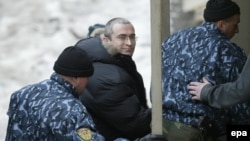 Former Yukos head Mikhail Khodorkovsky (center) is escorted into a court in Moscow in December 2003, less than two months after his arrest, for a hearing on prolonging his pretrial custody.