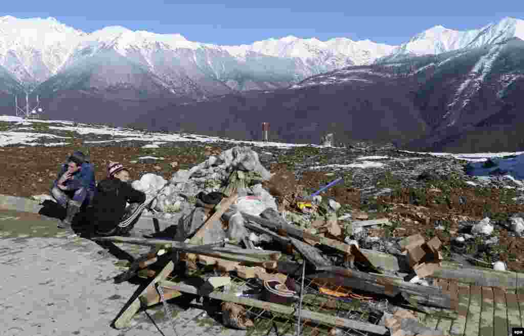 Workers sit next to a pile of rubble in the media village.