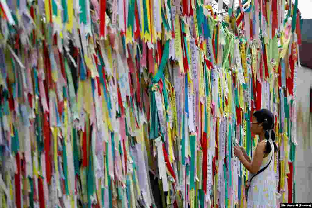 Një vajzë shikon një gardh me tela me gjemba, të zbukuruar me shirita që mbajnë mesazhe me dëshirën për bashkimin midis dy Koreve pranë zonës së çmilitarizuar që ndan dy shtetet në Paju të Koresë së Jugut.&nbsp;