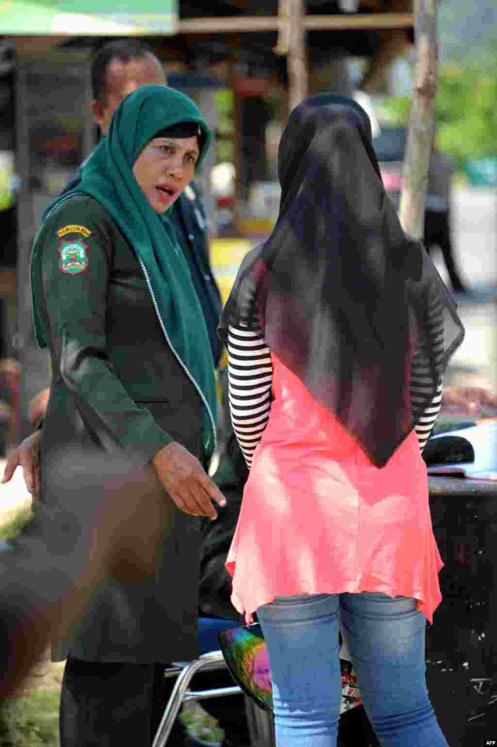 پلیس شریعت در حال تذکر دادن به یک زن اندونزیایی به خاطر پوشیدن شلوار جین تنگ