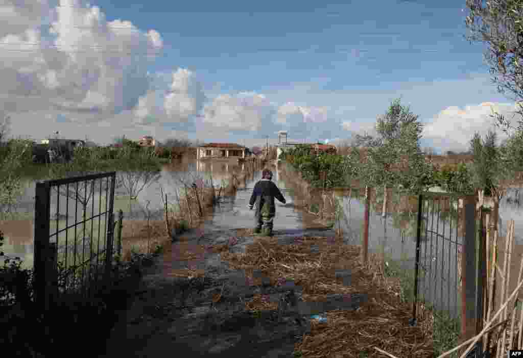 An Albanian man walks through floodwaters towards his home in the village of Mifol near the city of Vlora. (AFP/Gent Shkullaku)