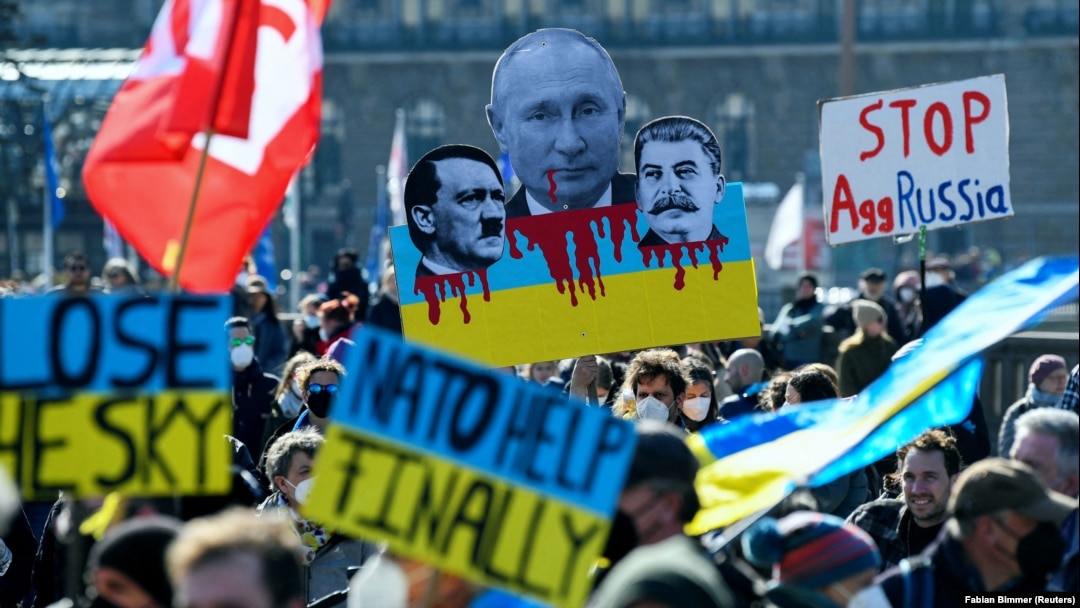 A protester holds up a sign with pictures of Russian President Vladimir Putin, Adolf Hitler, and Joseph Stalin, during an anti-war demonstration in Hamburg on March 20.