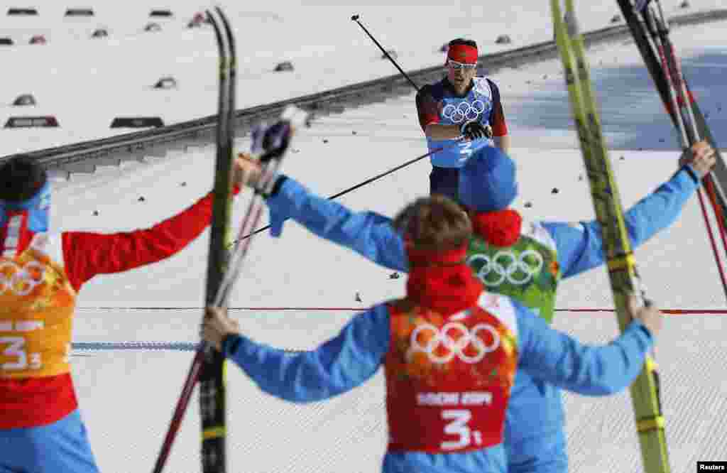 Russia&#39;s Maksim Vylegzhanin (top) crosses the finish line as his teammates celebrate during the men&#39;s relay 4x10-kilometer cross-country event. (Reuters/Stefan Wermuth)