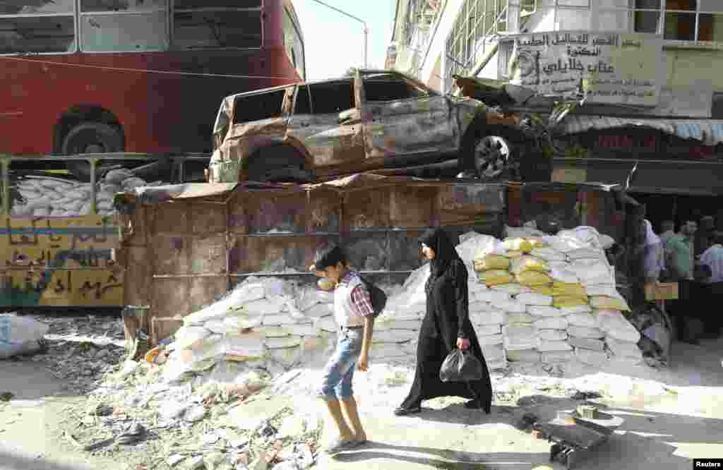 Syrians walk past sandbags as they shop before the time for iftar, or breaking fast, during the Muslim fasting month of Ramadan, at the Karaj Al-Hajez crossing in Aleppo. (Reuters/Muzaffar Salman&nbsp;)