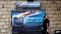 Israelis walk past a poster welcoming and supporting US President Donald Trump in downtown Jerusalem, May 19, 2017