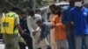 A worker offers hand sanitiser to those maintaining social distancing to buy groceries at a subsidised shop during the nationwide lockdown.