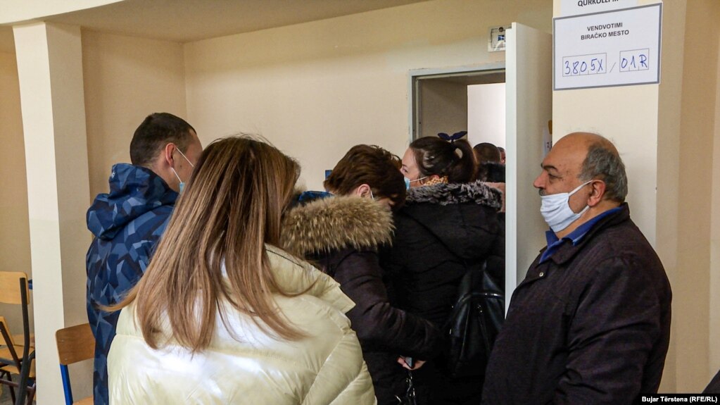 Votuesit me maska por pa mbajtur distancën presin për të votuar në një vendvotim në Mitrovicën Veriore.