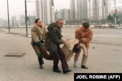 This photo, taken on March 8, 1993, shows people carrying away a man wounded by a shell that fell near the television station in Sarajevo.