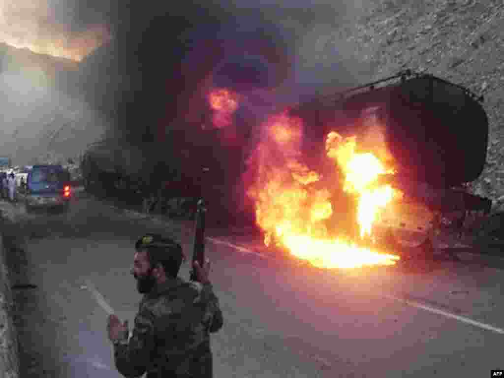 A soldier stands next to the wreckage of a burning truck transporting fuel for NATO operations on the Kabul-Jalalabad highway. (AFP photo/STR)