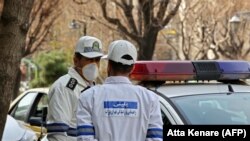 Emergency first responders wearing protective masks stand along a street in Tehran, February 24, 2020