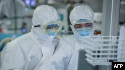 Dy punëtorë shëndetësorë brenda një laboratori në Kinë.