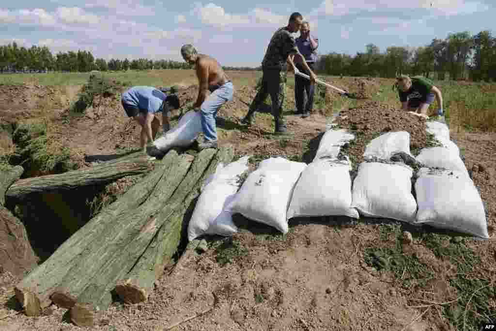 Жителі Маріуполя допомагають українським війсьвослужбовцям рити окопи і робити укріплення мішками з піском, 29 серпня 2014 року &nbsp;