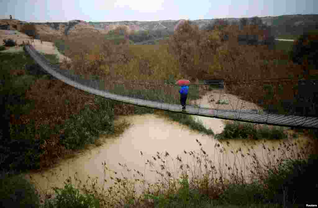A man walks on a bridge crossing over a stream near a Kibbutz in Israel's southern Negev desert. (Reuters/Amir Cohen)