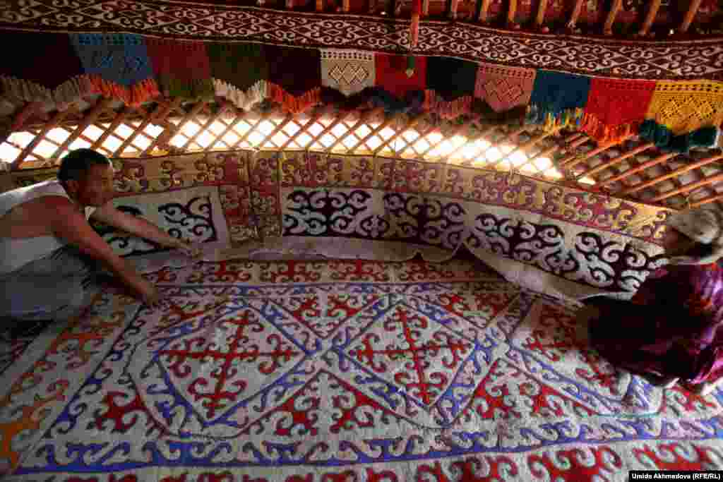 Dulat and Farid lay down a handmade carpet made by women living in the village of Rahat.