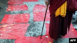 Tibetan Buddhist monk in exile walks over Chinese national flags as part of a protest in Dharamsala in March 2008.