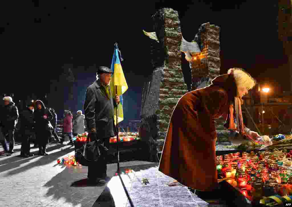 A woman lays a piece of bread next to candles during a ceremony in memory of the victims of the Holodomor famine in Kyiv on November 26. (AFP/Sergei Supinsky)