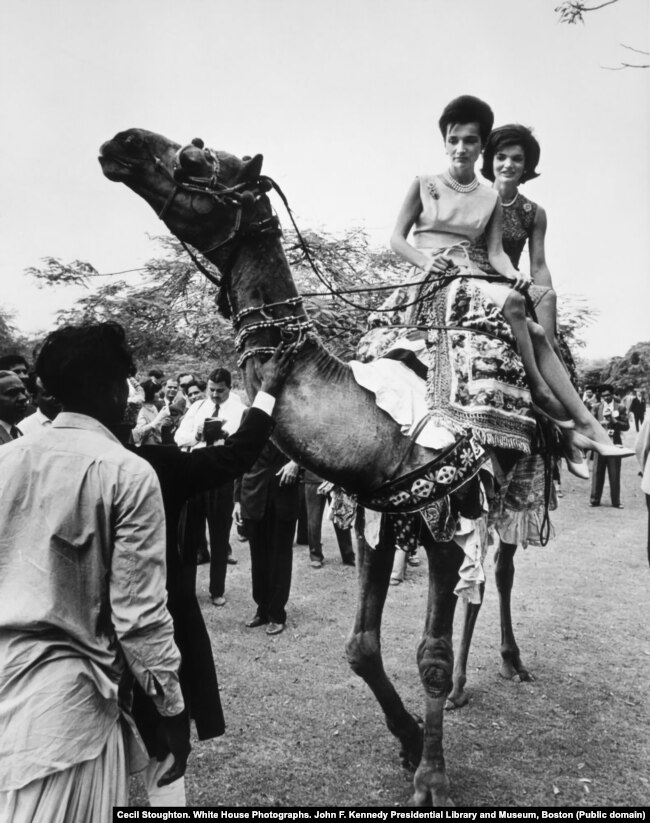 Kennedy (right) and Radziwill ride Ahmad's camel. Video shows the women sitting atop the kneeling camel, asking its handler to make it stand. After a nervous glance at the ladies' American minders, Ahmad ordered the loudly groaning camel up and the sisters made a brief tour of the grounds.