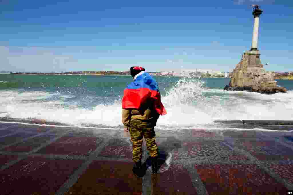 A man draped in the Russian flag stands on the coast of Sevastopol on a stormy day in March. With the Crimean Peninsula firmly under Russian control, on April 7 the stage was set for war when pro-Russian groups in&nbsp;Donetsk and Luhansk burst into government offices and helped themselves to weaponry. Kyiv responded by announcing the start of a &quot;counterterrorism&quot; operation.