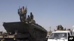 Syrian soldiers stand atop an armored vehicle on August 10.