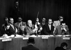 Уоррен Остин, представитель США в Организации Объединенных Наций, держит в руках оружие советского производства ППШ, известное как «пистолет-пулемет», который американские военные захватили в Корее. Оружие было продемонстрировано как свидетельство того, что Сталин поддерживал вторжение коммунистических сил.
