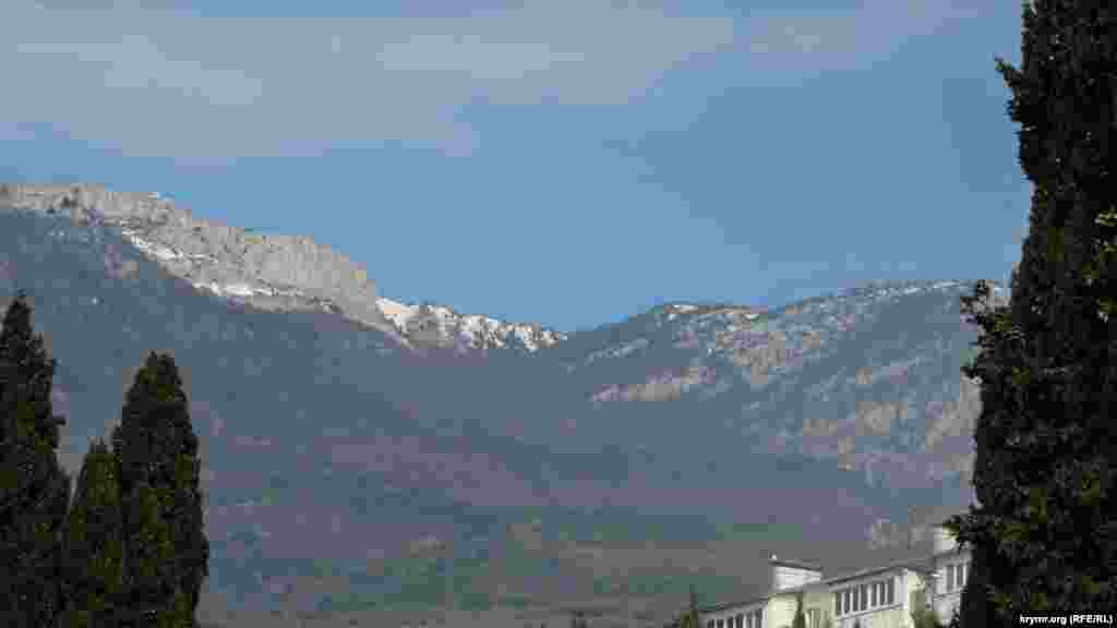 Снежные вершины гор нависают над маленьким курортным поселком, защищая его от ветра