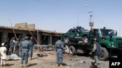 Police officers and security officials clear the debris after a suicide blast in Lashkar Gah, which killed five people. 