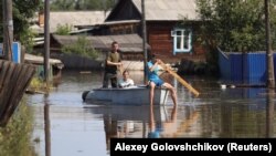 Local residents navigate the flood waters in Oktyabrsky in the Irkutsk region.
