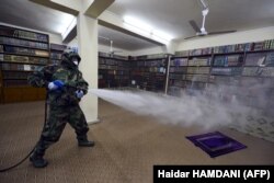 Член иранской гражданской обороны распыляет дезинфицирующее средство в помещении религиозной библиотеки. Эн-Наджаф, Иран, 9 марта 2020 года.