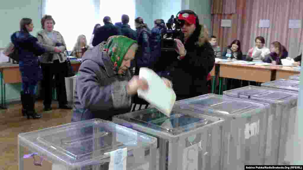 Пожилая женщина бросет бюллетень в урну для голосования. Киев, 26 октября 2014 года.