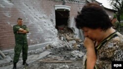 Иллюстративное фото. Женщина возле поврежденного дома в Донецке. Июль 2016 года