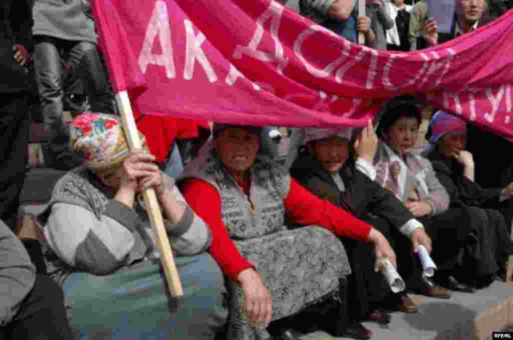 Участницы акции протеста держат транспарант с надписью, призывающей Аскара Акаева уйти в отставку.