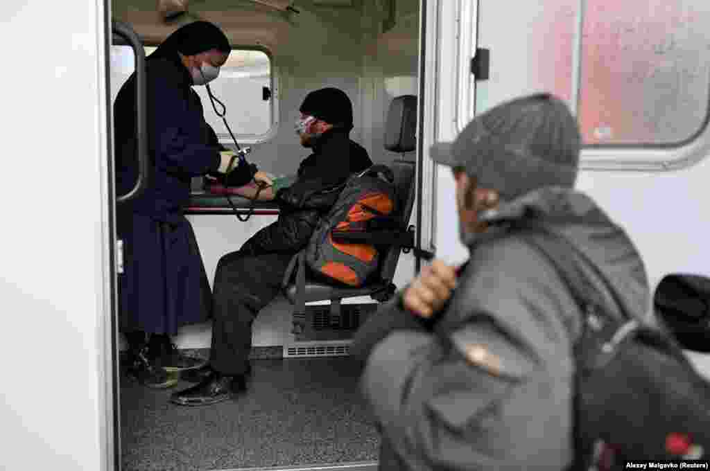 A nun checks the blood pressure of a man who is homeless during a charity event organized by Caritas.