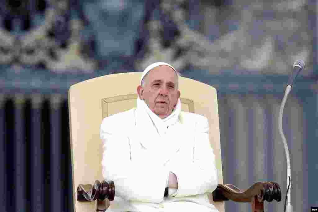 A chilly Pope Francis slips his hands into the sleeves of a white coat on St. Peter's Square during the weekly Wednesday General Audience at the Vatican on November 27. (EPA/Fabio Frustaci)
