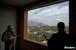 Separatiști în Donețk privesc spre fumul ce se ridică din aeroportul internațional Serghei Prokofiev, controlat de forțele guvernamentale, 23 sept., 2014