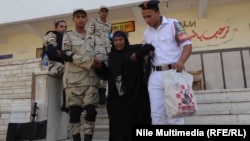 عناصر من قوات الأمن المصرية تساعد سيدة بعد الإدلاء بصوتها في الإنتخابات