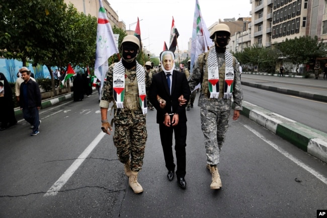 Anëtarët e forcës paramilitare iraniane, Basij, të veshur në stilin e militantëve palestinezë dhe libanezë, interpretojnë arrestimin e kryeministrit të Izraelit, Benjamin Netanyahu, gjatë një tubimi pro-palestinez në Teheran, 13 tetor 2023.